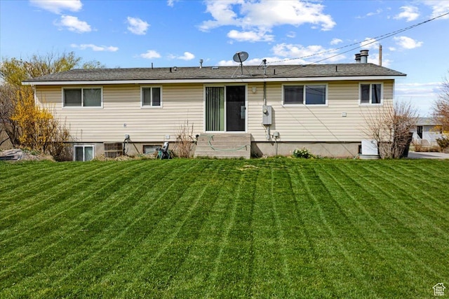 back of property with entry steps and a lawn