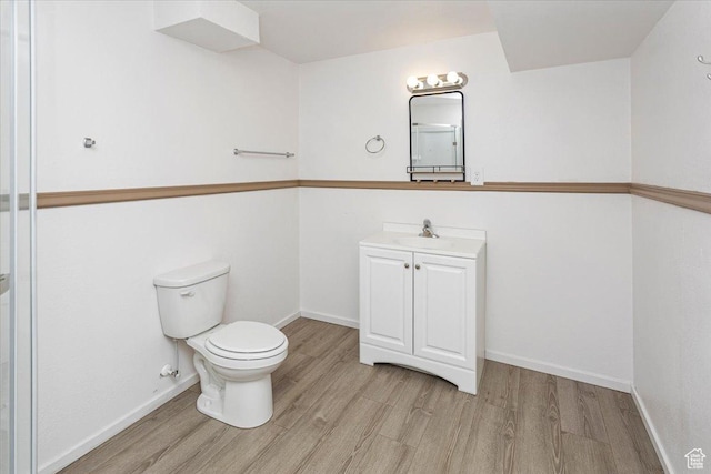 bathroom featuring toilet, wood finished floors, vanity, and baseboards