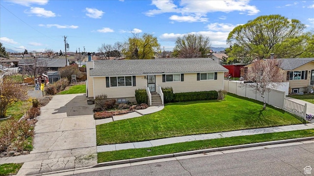 raised ranch with a residential view, fence, and a front lawn