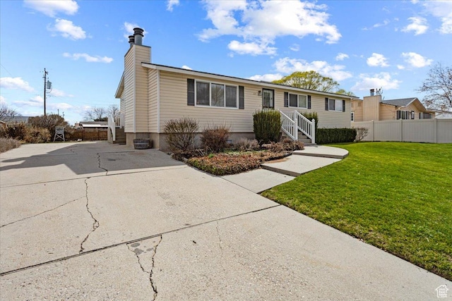 view of front of property featuring a front yard, driveway, fence, and a chimney