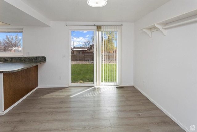 unfurnished dining area featuring baseboards and wood finished floors