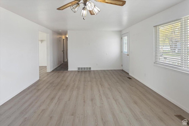 unfurnished room with light wood-style floors, baseboards, a ceiling fan, and visible vents