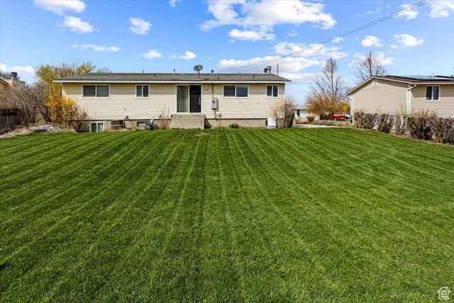 back of house with entry steps and a lawn