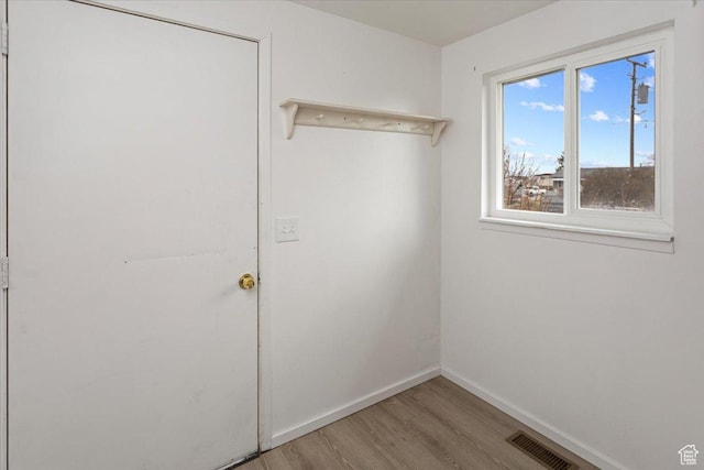 interior space with wood finished floors, baseboards, and visible vents