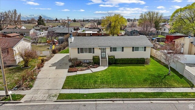 single story home with a mountain view, fence, a front lawn, a residential view, and roof with shingles