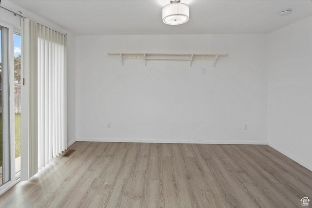 unfurnished room with light wood finished floors, baseboards, visible vents, and a wealth of natural light