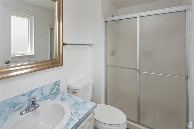 bathroom featuring toilet, vanity, and a stall shower