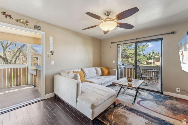 living area featuring baseboards, a ceiling fan, and dark wood-style floors