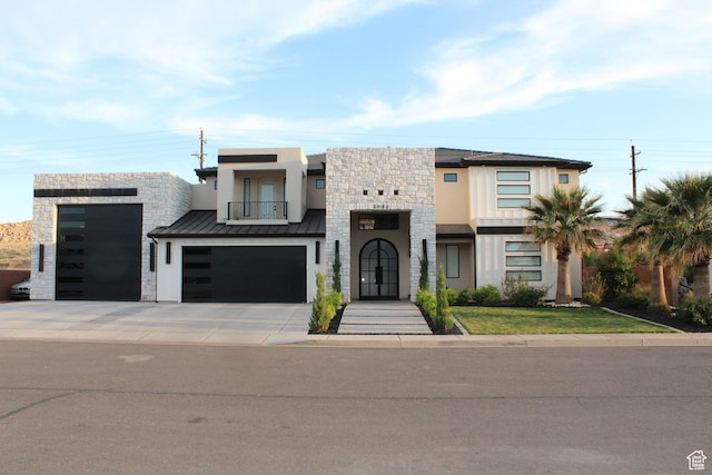 modern home with stucco siding, stone siding, driveway, and a balcony