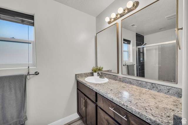 bathroom featuring baseboards, a textured ceiling, a stall shower, and vanity