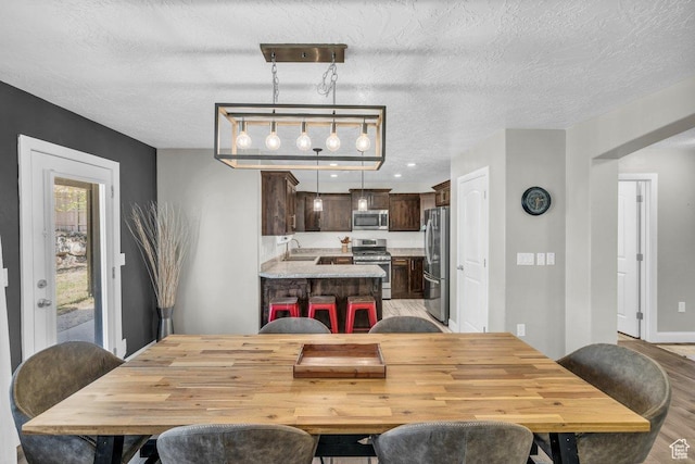 dining area with light wood-style flooring and a textured ceiling