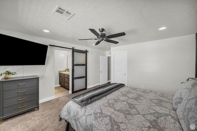 carpeted bedroom featuring baseboards, recessed lighting, a textured ceiling, a barn door, and visible vents
