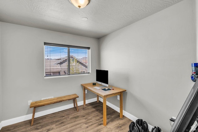 office featuring light wood-type flooring, baseboards, and a textured ceiling