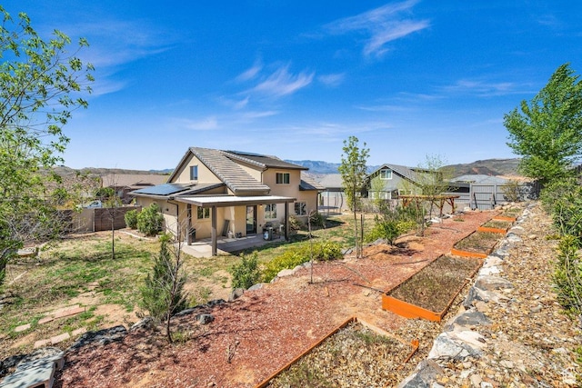 back of house with roof mounted solar panels, a fenced backyard, stucco siding, a patio area, and a tile roof