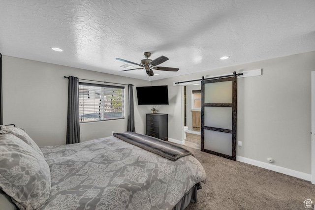bedroom featuring carpet flooring, a barn door, baseboards, and a textured ceiling