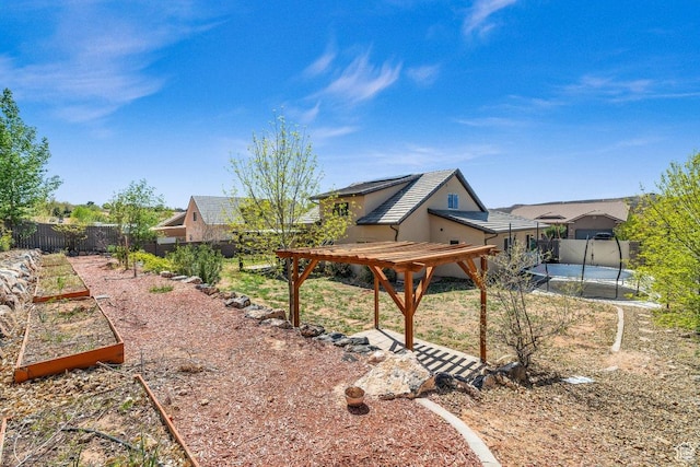 view of yard with a pergola, a trampoline, a fenced backyard, and a garden