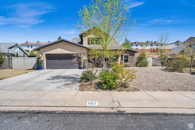 view of front facade with an attached garage, driveway, stucco siding, and fence