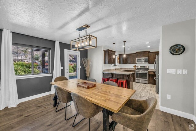 dining area with recessed lighting, light wood-type flooring, baseboards, and a textured ceiling