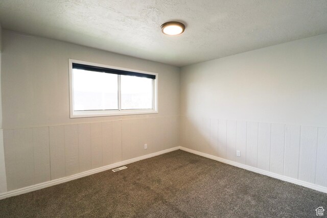 4503 S 2025 W, Roy, UT 84067 - spare room with a textured ceiling, dark colored carpet, visible vents, and wood walls