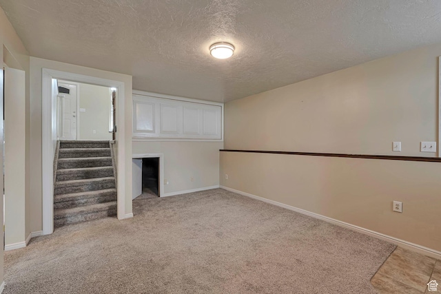 unfurnished living room featuring baseboards, stairs, light carpet, and a textured ceiling