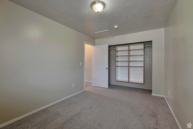 unfurnished bedroom with carpet flooring, visible vents, a textured ceiling, and baseboards
