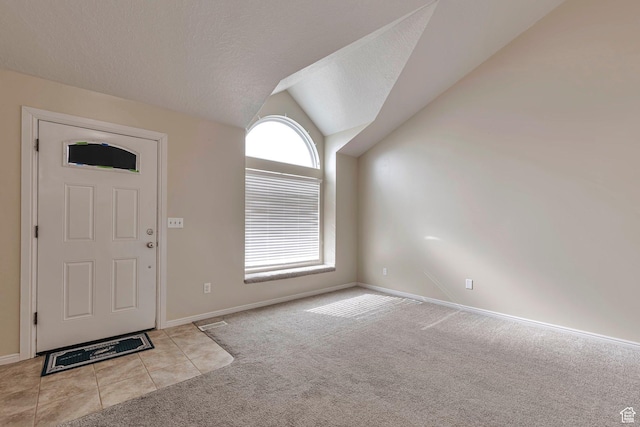 carpeted foyer entrance featuring tile patterned flooring, baseboards, a textured ceiling, and lofted ceiling