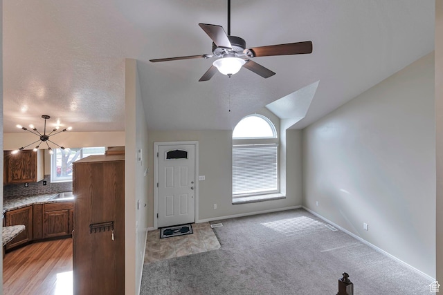 entryway featuring a healthy amount of sunlight, ceiling fan with notable chandelier, baseboards, and lofted ceiling