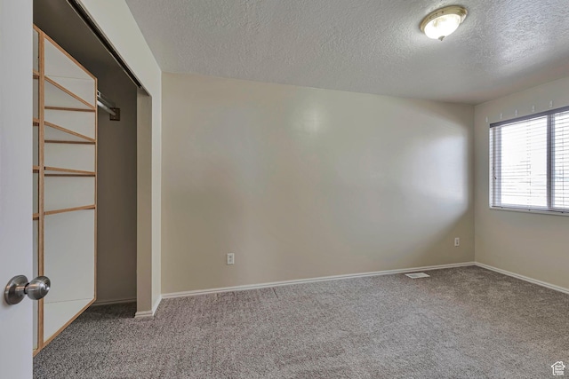 interior space with carpet floors, baseboards, visible vents, and a textured ceiling