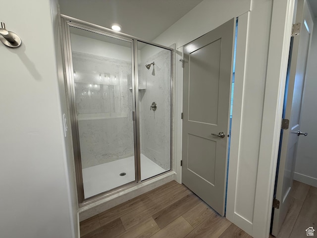 bathroom with a stall shower and wood finished floors