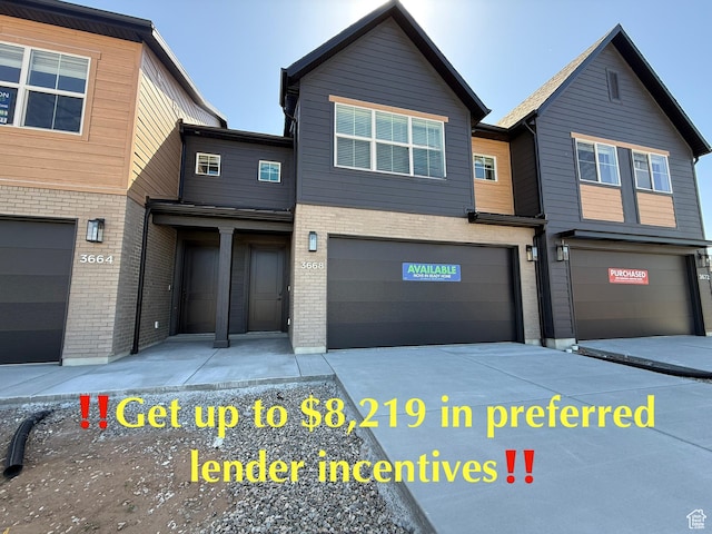 multi unit property with an attached garage, brick siding, and driveway