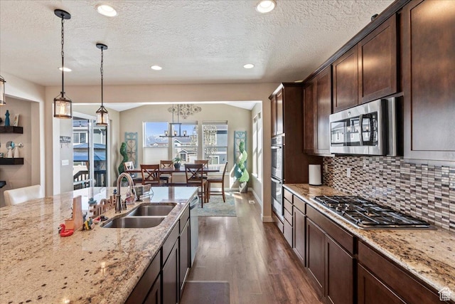 12133 S Broken Arch Ln, Herriman, UT 84096 - kitchen with dark wood finished floors, dark brown cabinetry, appliances with stainless steel finishes, a sink, and decorative backsplash