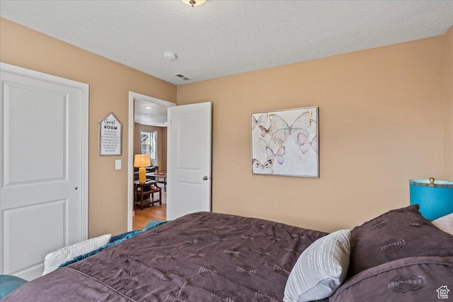 12133 S Broken Arch Ln, Herriman, UT 84096 - bedroom with visible vents, wood finished floors, and a textured ceiling