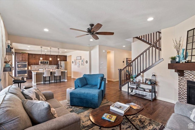 12133 S Broken Arch Ln, Herriman, UT 84096 - living room with ceiling fan, baseboards, dark wood-style floors, and stairway