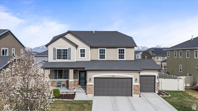 view of front facade featuring driveway, stone siding, fence, and a front lawn