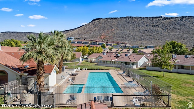 pool featuring a residential view, a mountain view, a patio area, fence, and a lawn