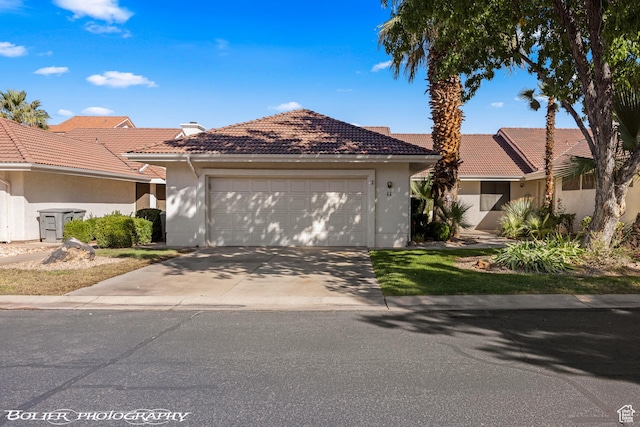 ranch-style house featuring a garage, stucco siding, concrete driveway, and a tile roof
