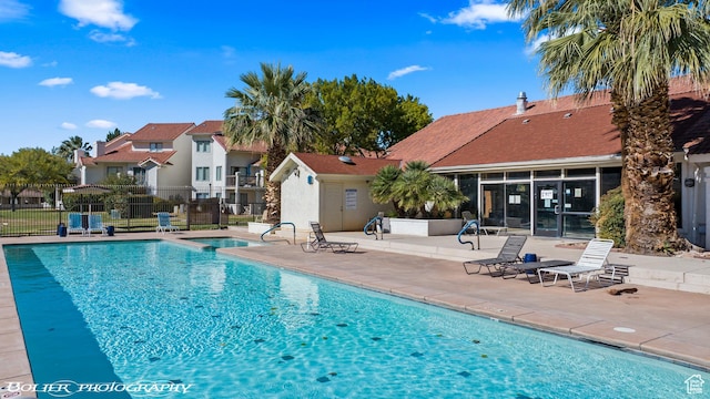 community pool with a patio area and fence