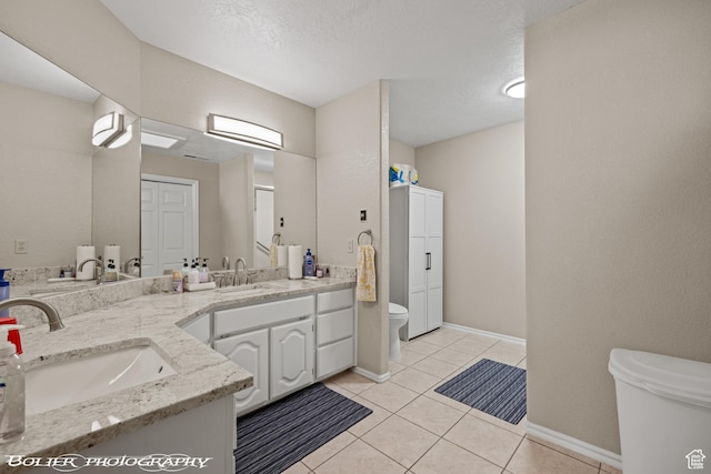 bathroom featuring toilet, tile patterned floors, double vanity, and a sink