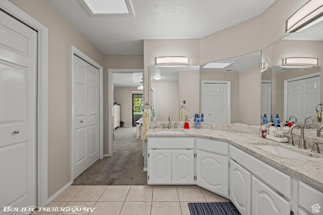 full bathroom featuring a closet, double vanity, a sink, and tile patterned flooring