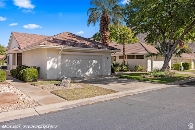view of front facade featuring an attached garage, driveway, stucco siding, and a tile roof