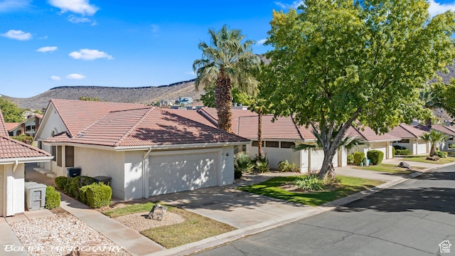 view of front of house featuring a garage, stucco siding, a tile roof, a mountain view, and concrete driveway