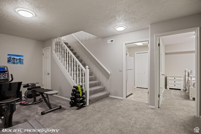 interior space featuring carpet, visible vents, a textured ceiling, and baseboards