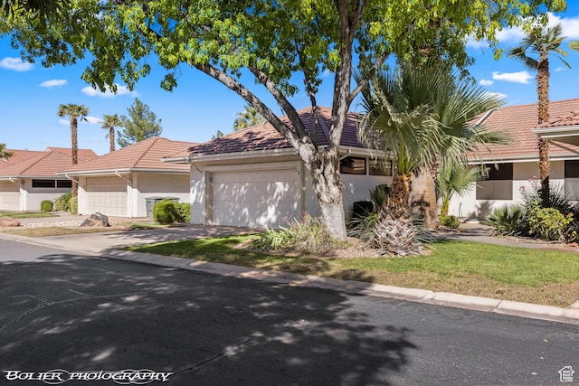 view of front facade featuring a tile roof, an attached garage, driveway, and stucco siding