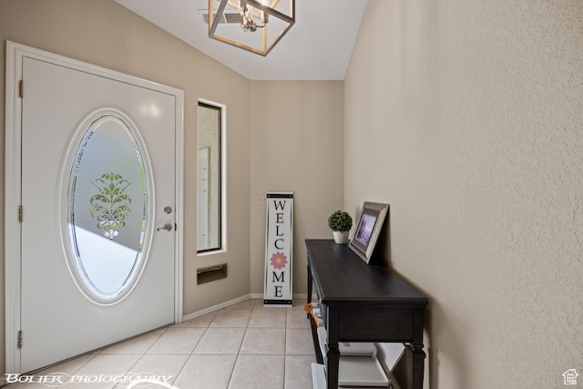 entrance foyer featuring light tile patterned floors, baseboards, and a chandelier