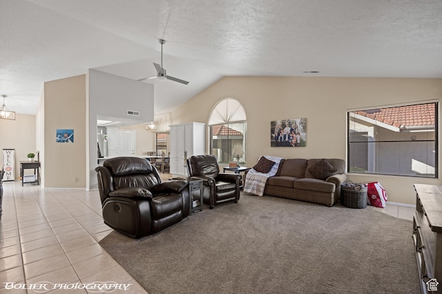 living area with light tile patterned floors, a textured ceiling, a ceiling fan, visible vents, and vaulted ceiling