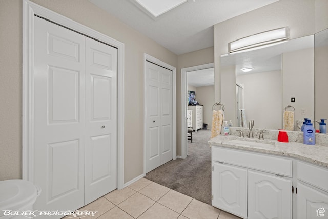 bathroom featuring tile patterned flooring, vanity, a closet, and baseboards