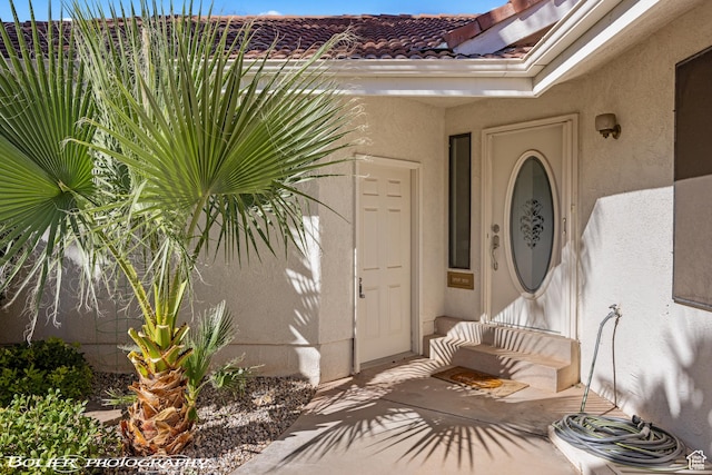 view of exterior entry featuring stucco siding and a tiled roof