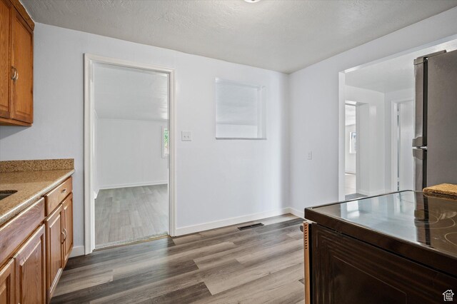 940 Fillmore Ave, Ogden, UT 84404 - kitchen featuring light wood finished floors, freestanding refrigerator, black range with electric stovetop, brown cabinetry, and baseboards