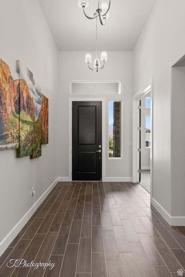 foyer entrance with wood finish floors, a notable chandelier, and baseboards