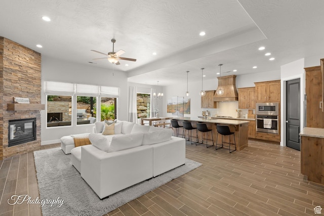 living area with light wood-style flooring, a fireplace, a ceiling fan, and recessed lighting